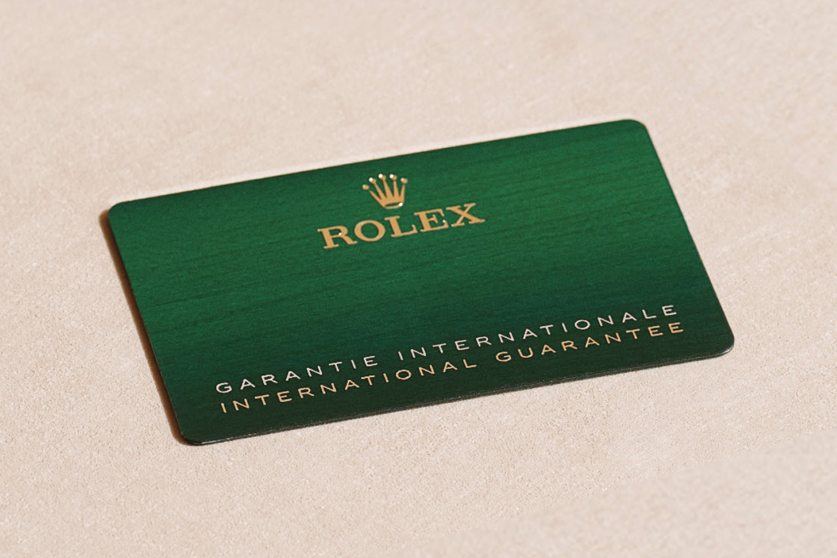 Green Rolex international guarantee card on a beige surface